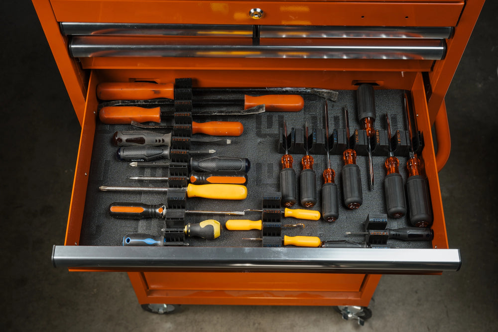 Orange toolbox with open drawer containing various tools on a dark background