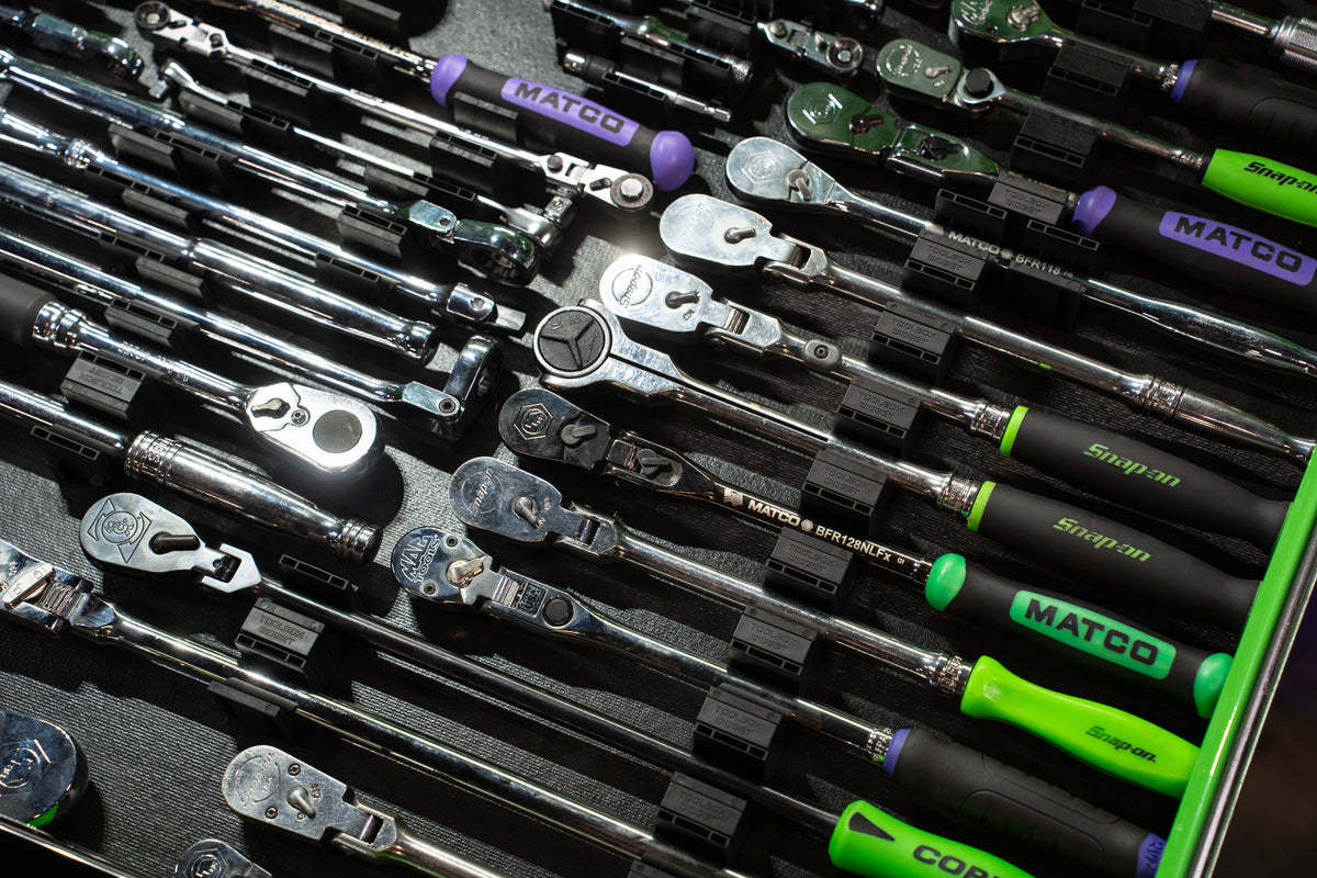 A close-up of a tool tray filled with multiple ratchets and wrenches, including visible brands such as MATCO and Snap-on. 