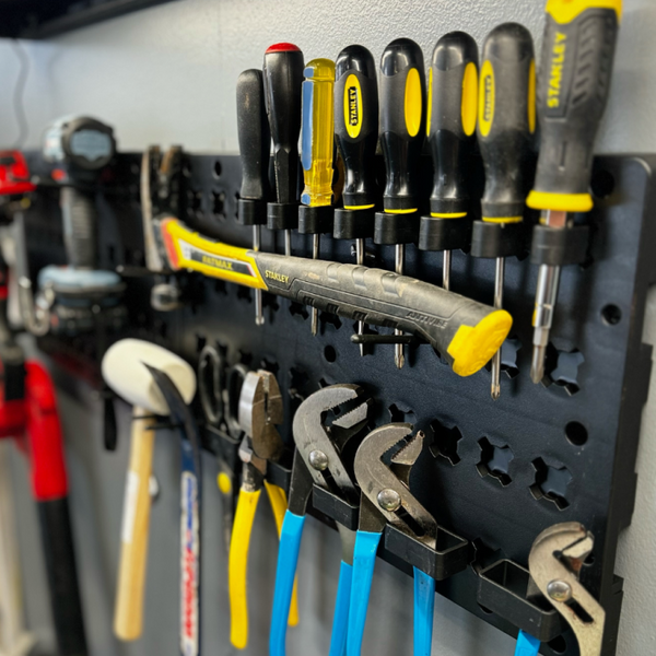 Wall-mounted tool organizer with various tools including screwdrivers and pliers.